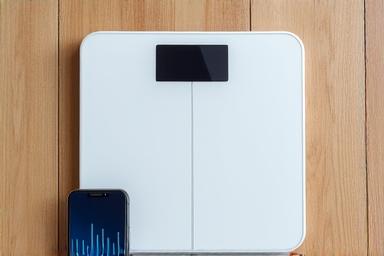 Close up of a smart scale and mobile phone fitness app
